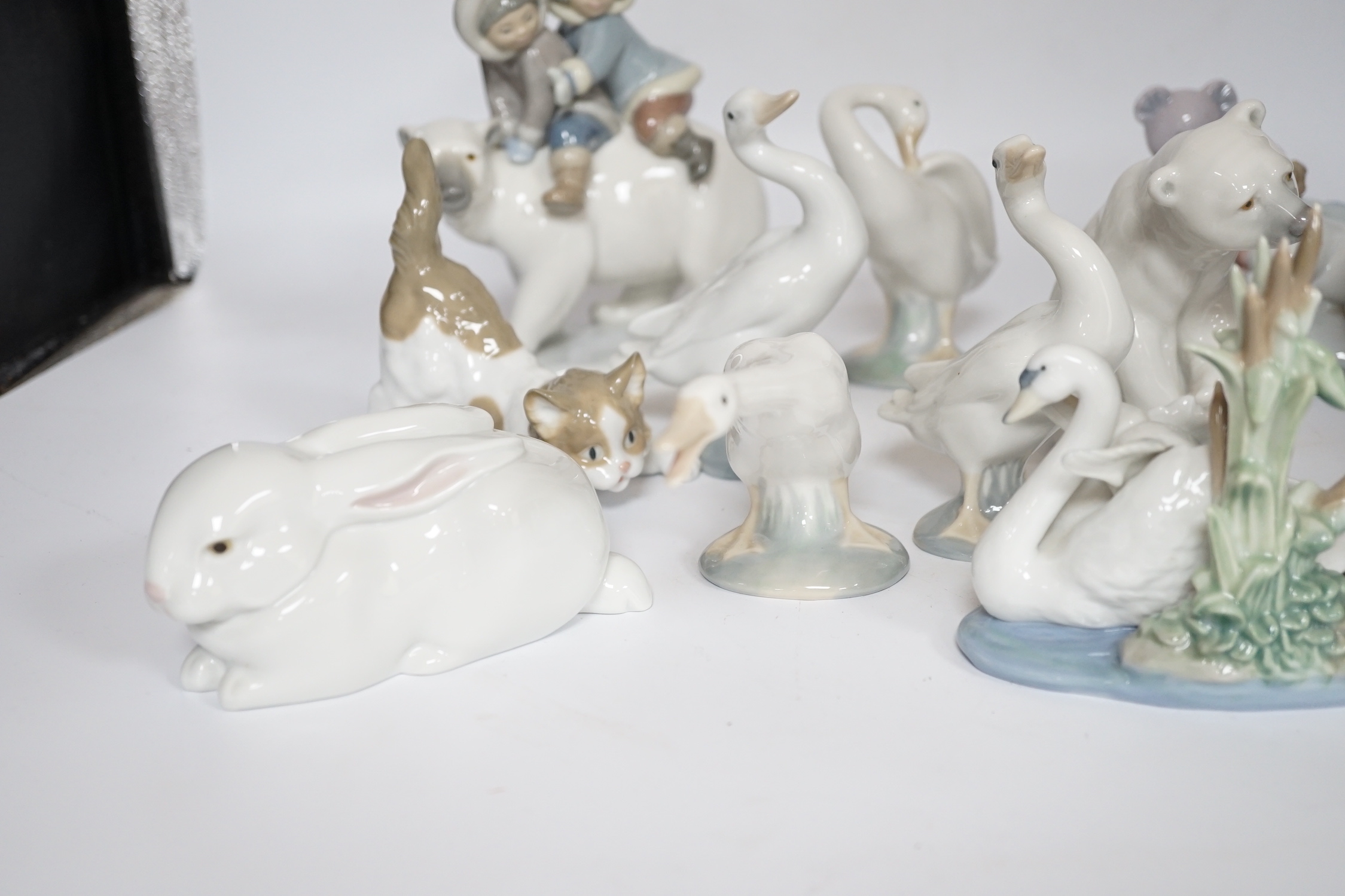 Eleven Lladro figure groups, including a collection of ducks, two Eskimo figure groups, a sleeping child with teddy on a cushion etc, none boxed